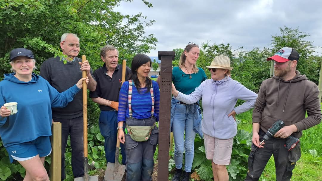 A group of six people smiling in a garden.