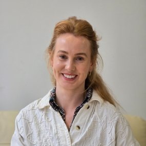 Smiling woman with long hair wearing a white shirt.