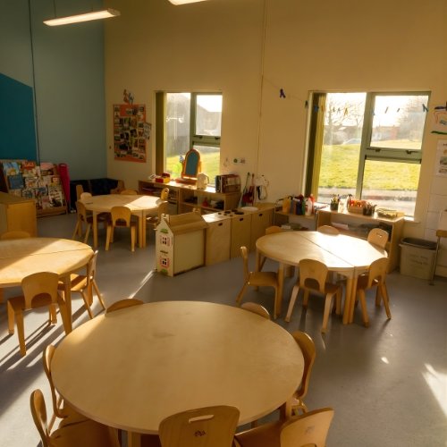 Bright classroom with wooden tables and chairs.
